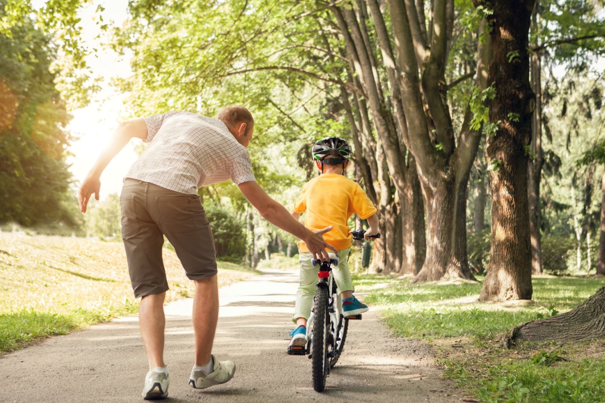 A father teaching a child to ride a bike.
