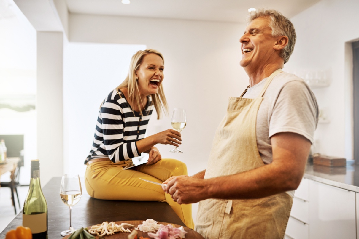 A couple laughing together in their kitchen.